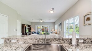 A kitchen with granite countertops, a stainless steel sink, and a ceiling fan. - Gulf Walk 506 (Miramar Beach)
