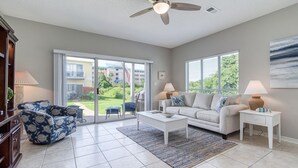 A spacious living room with a ceiling fan, a sofa, a coffee table, and a TV. - Gulf Walk 506 (Miramar Beach)