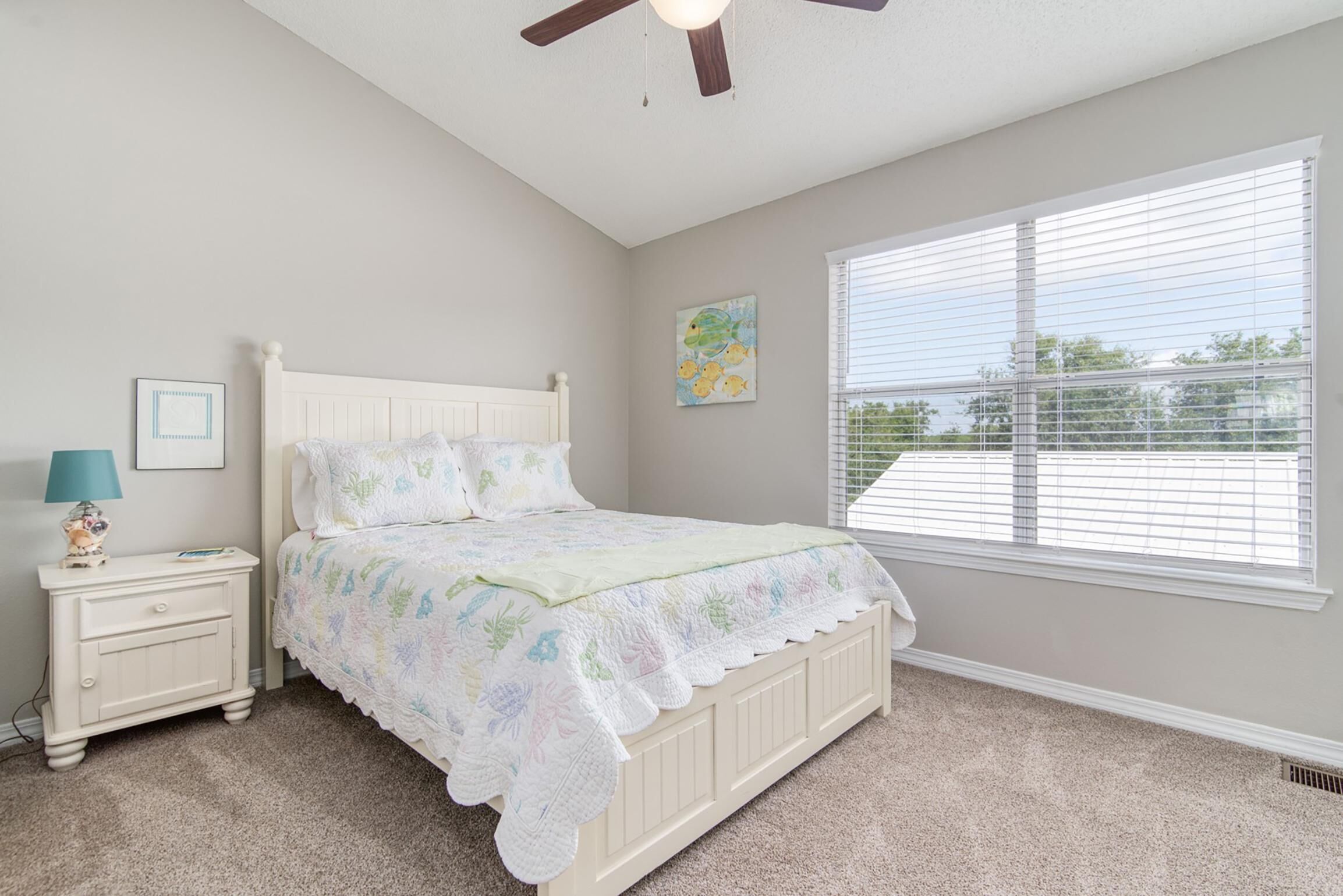 A bedroom with a bed, nightstand, lamp, and window with blinds.