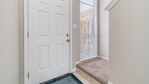 A white door with a doorknob, a window with blinds, and a carpeted bench. - Gulf Walk 506 (Miramar Beach)