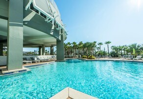 Ein Pool mit Liegestühlen und Palmen im Hintergrund.
