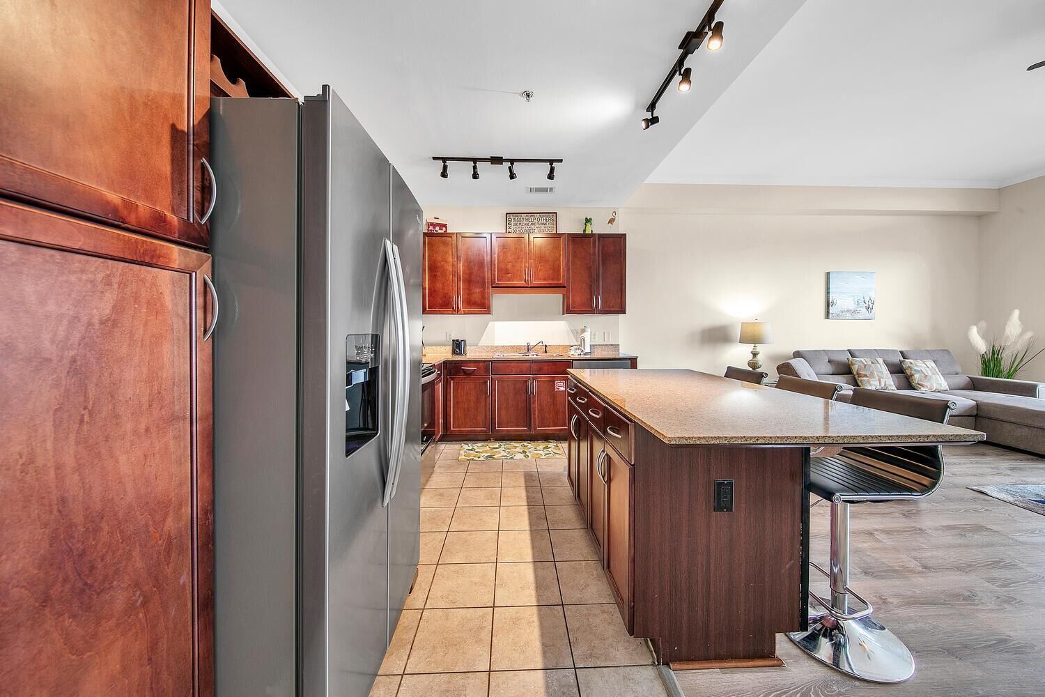 A modern kitchen with a stainless steel refrigerator, wooden cabinets, and a central island.