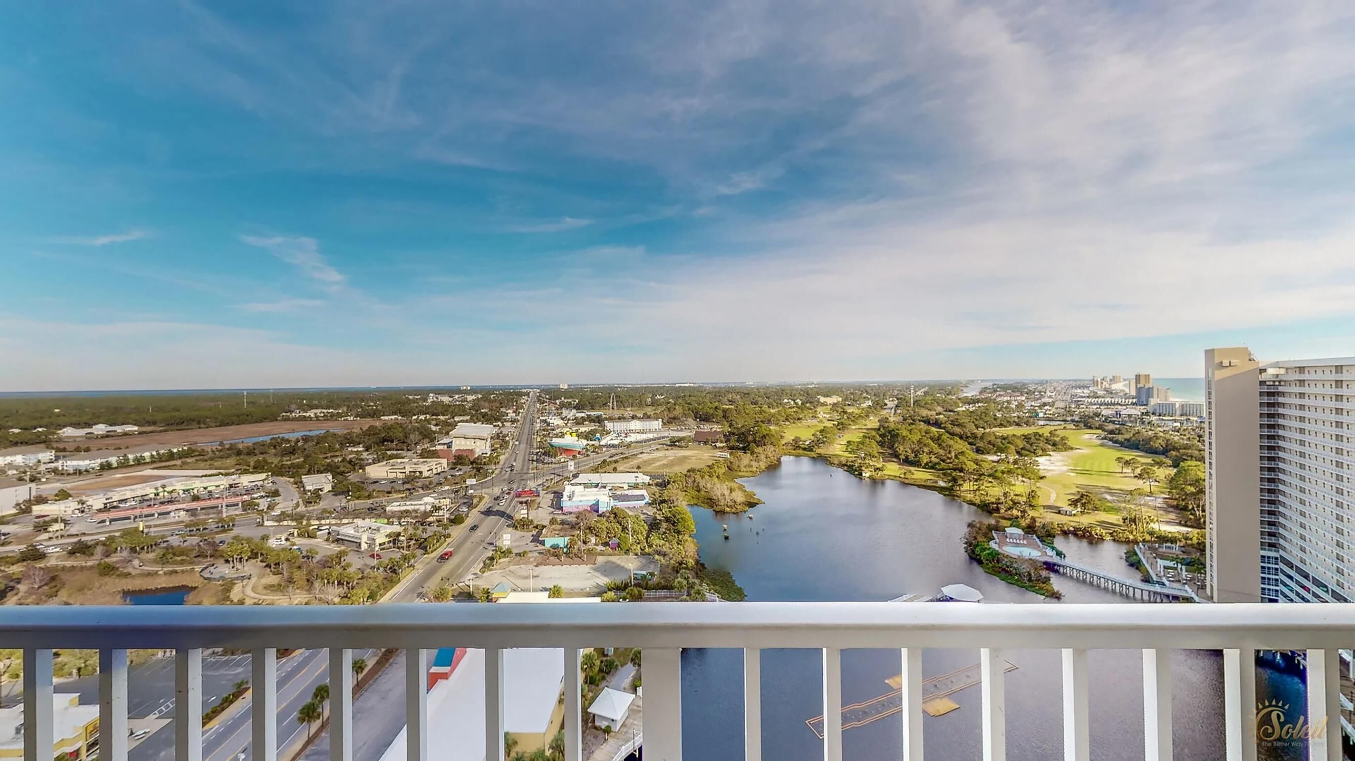 A high-rise hotel overlooking a cityscape with a river, roads, and greenery.