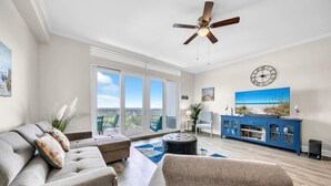 A modern living room with a grey sofa, a blue entertainment unit, and a ceiling fan.