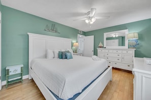 Une chambre à coucher avec un grand lit, une tête de lit blanche et un ventilateur de plafond.