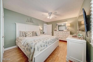 Ein Schlafzimmer mit Bett, Kommode, Schminktisch und Deckenventilator.