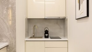 Uma cozinha compacta com pia, torneira e cafeteira.