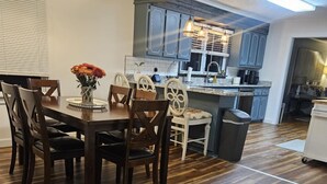 A modern kitchen with dark wooden cabinets, a central island, and a dining area with a wooden table and chairs. - MARGARET'S PLACE ON SUNNYSIDE. A charming home for countryside relaxation (Greeneville)