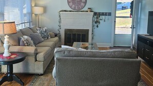 A living room with a fireplace, a clock, and a sofa. - MARGARET'S PLACE ON SUNNYSIDE. A charming home for countryside relaxation (Greeneville)