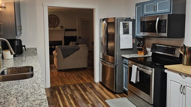 A modern kitchen with granite countertops, stainless steel appliances, and a wooden floor. - MARGARET'S PLACE ON SUNNYSIDE. A charming home for countryside relaxation (Greeneville)