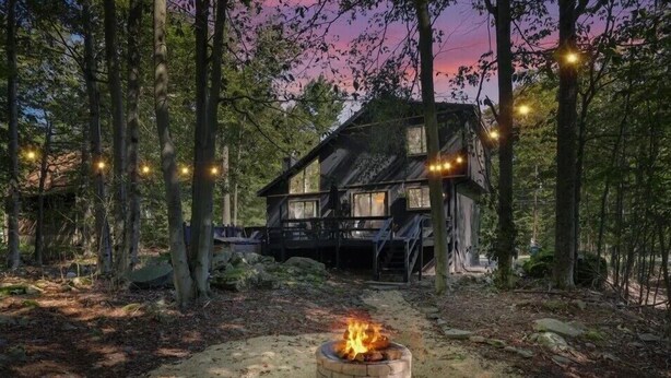 A rustic cabin surrounded by trees with a fire pit in the foreground. - Fantastic 3-bedroom house in Tobyhanna close to all major attractions. (Tobyhanna)