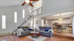 A spacious living room with a large sectional sofa, a round coffee table, and a staircase leading to an upper level. - Fantastic 3-bedroom house in Tobyhanna close to all major attractions. (Tobyhanna)