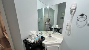 Un baño con lavamanos, espejo, toallero y secador de pelo.