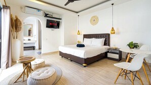 A modern hotel room with a large bed, a desk, a chair, a ceiling fan, and a TV displaying 'NETFLIX'.