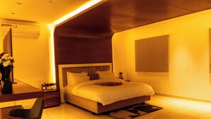 A modern bedroom with a large bed, a desk, and a chair. - Tchetche Hotel & Restaurant (Accra)