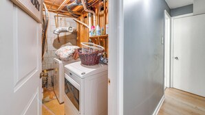 A laundry room with a washing machine, a basket, and a shelf with cleaning supplies. - Lakefront Guest Suite Near Richmond (Richmond)