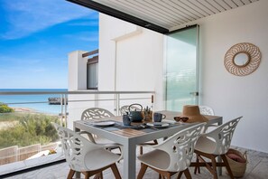Un balcon avec une table dressée pour le dîner, offrant une vue sur la côte.