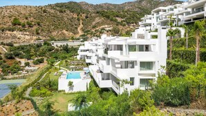 A modern white building with multiple balconies, a swimming pool, and a tennis court. - Hillside Flat With Pool in Palo Alto - Ref M49 (Ojén)