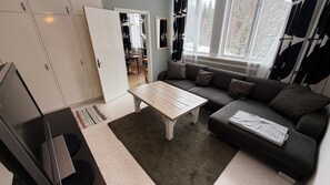 Ein Wohnzimmer mit einer Couch, einem Couchtisch, einem Fernseher und einem Kleiderschrank.
