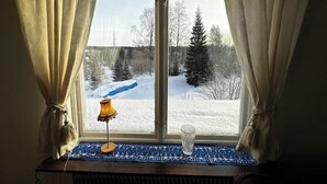 Ein Fenster mit Vorhängen, einer Lampe und einem Glas auf dem Fensterbrett.