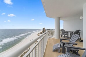 A balcony with a view of the beach and ocean, featuring Adirondack chairs and a table. - Palacio 1704 (Pensacola)