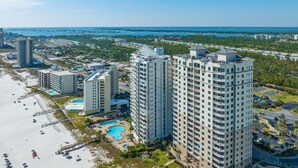 Un hôtel de grande hauteur, avec de nombreux étages, une piscine et une vue sur la plage.