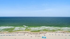 Une plage avec un ciel dégagé, une mer calme et de nombreux transats et parasols.