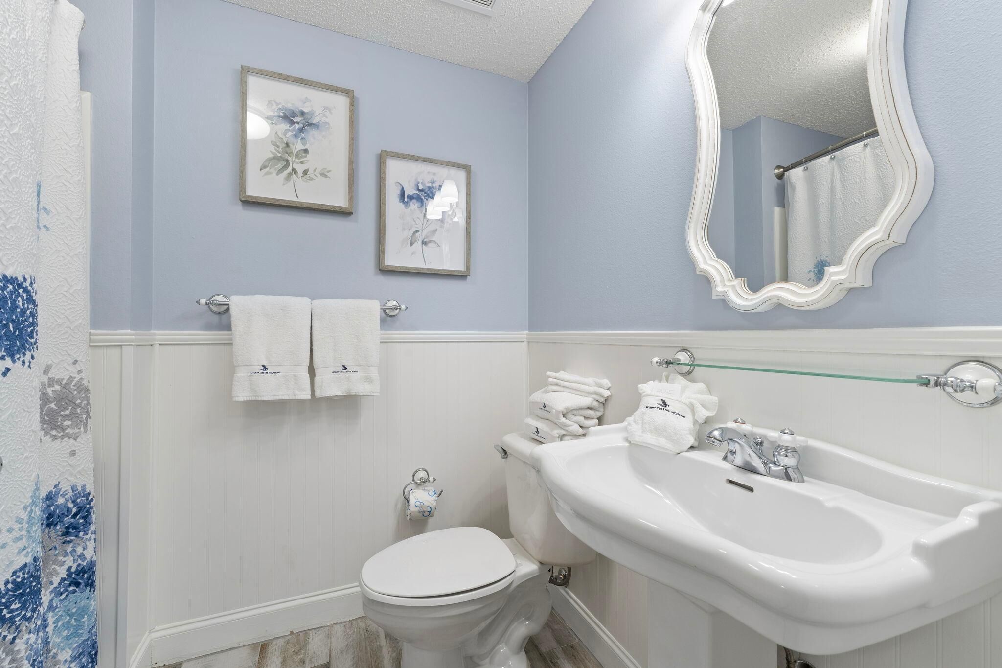 A bathroom with a toilet, sink, and two framed floral pictures on the wall.