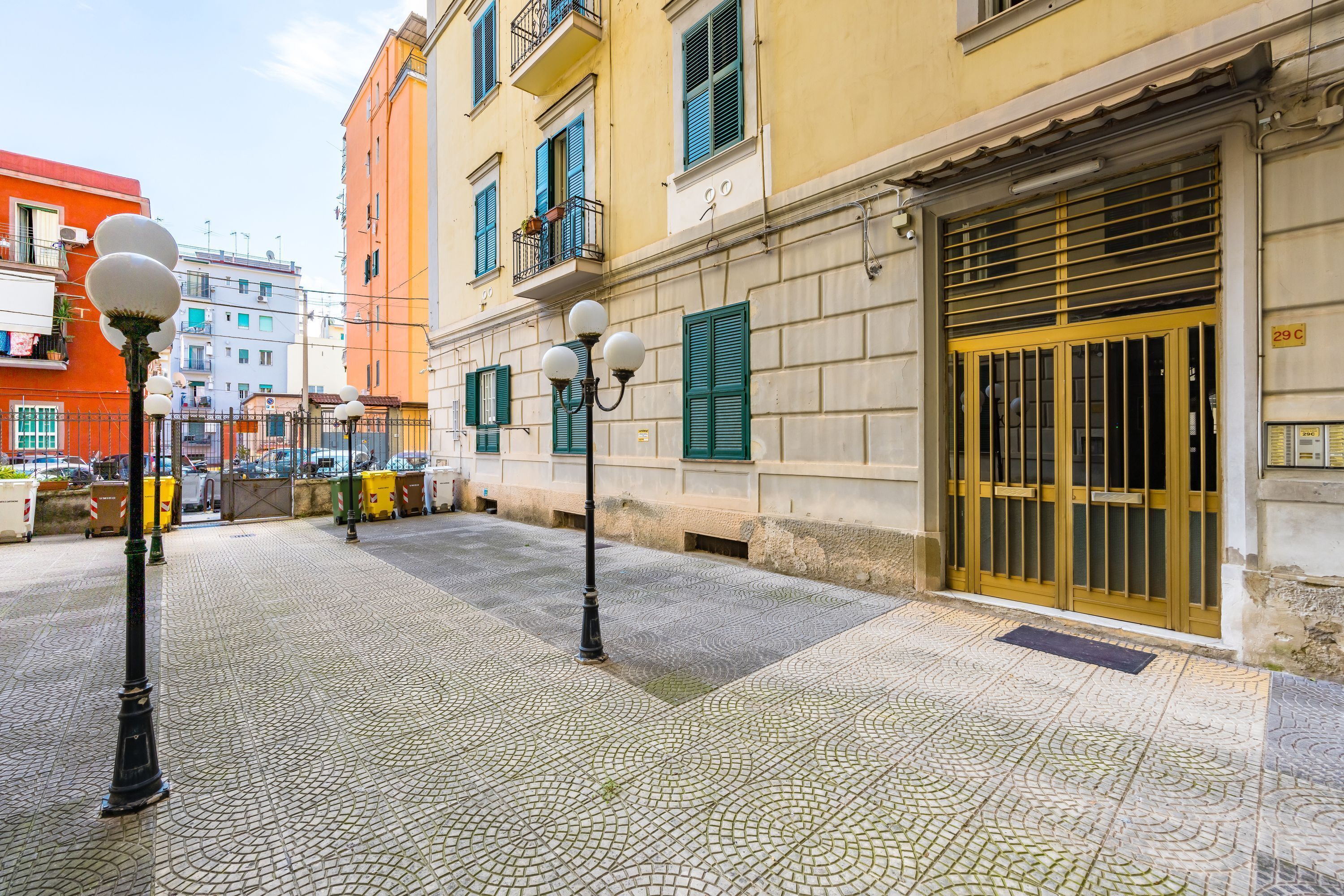 Uma rua de paralelepípedos com um edifício com porta amarela e persianas verdes.