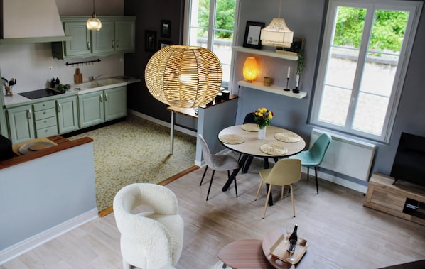 A modern kitchen with light green cabinets, a dining area with a round table and chairs, and a large window providing natural light.