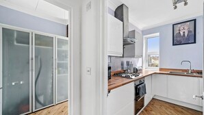 A modern kitchen with white cabinets, a wooden countertop, and a stainless steel range hood.
