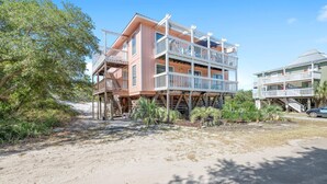 A beachfront property with multiple levels, outdoor balconies, and a sandy beach area. - Romar Village 112 (Orange Beach)