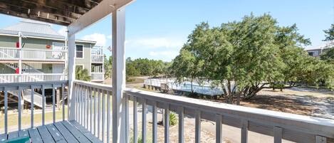 A wooden deck with a view of a building with multiple balconies and a tree.