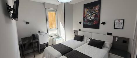 A modern hotel room with two beds, a desk, and a window.