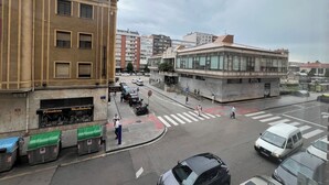 Straßenansicht mit Gebäuden, einer Fußgängerampel und parkenden Autos.