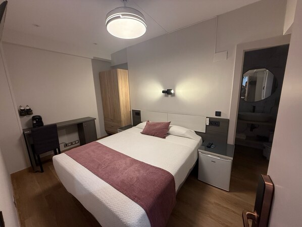 A modern hotel room with a large bed, bedside table, and a small bedside unit. - PLAZA SANTANDER (Santander)