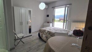A bedroom with a bed, a chair, a wardrobe, and a table with a glass of red wine. - VILLA FIORITA LAKE VIEW APARTMENT (Avigliana)