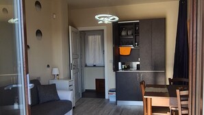 A modern living space with a sofa, dining table, and kitchen area. - VILLA FIORITA LAKE VIEW APARTMENT (Avigliana)