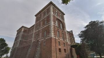Un grand bâtiment en briques, doté de nombreuses fenêtres et d’un escalier central.
