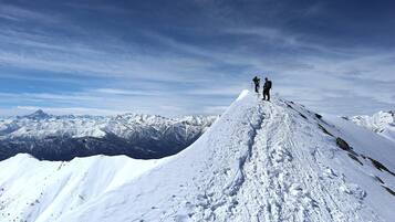 A snowy mountain peak with two hikers at the summit.