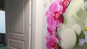 A room with a door, a wall with a floral mural, and a green towel on a surface. - VILLA FIORITA LAKE VIEW APARTMENT (Avigliana)