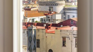 A cityscape with a prominent mountain in the background, viewed through a window with curtains. - Sunny Panoramic Apartment by Napoliapartments (Naples)