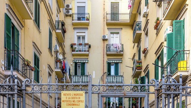 A gated entrance to a building with balconies, a sign indicating no entry for motorcycles, and a yellow vehicle parked nearby. - Sunny Panoramic Apartment by Napoliapartments (Naples)