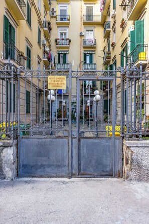 A gated entrance to a building with balconies, a sign indicating no entry for motorcycles, and a yellow vehicle parked nearby. - Sunny Panoramic Apartment by Napoliapartments (Naples)