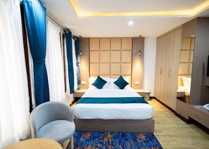 Una habitación de hotel con una cama grande, una silla, un escritorio y un armario.