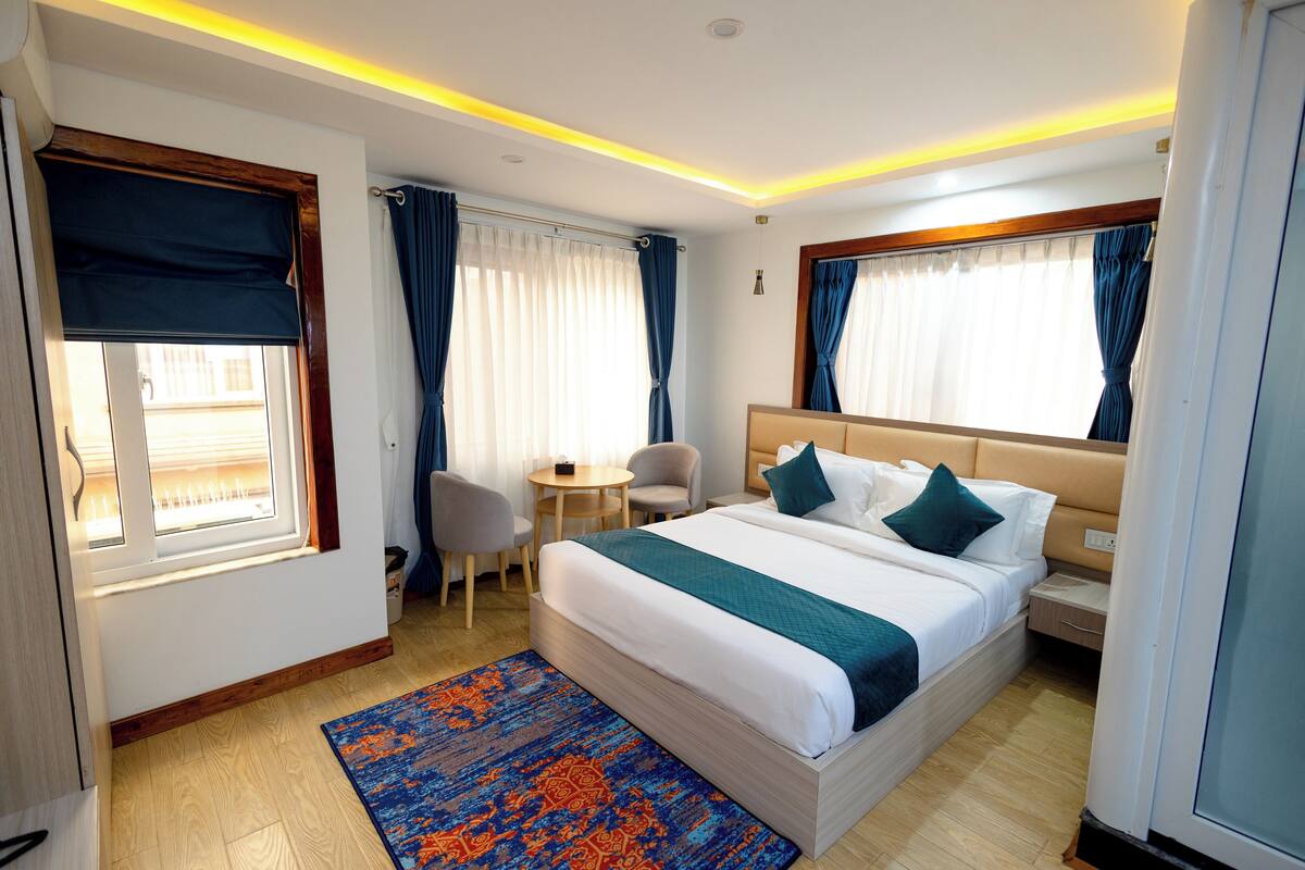 A hotel room with a bed, a desk, a chair, and a window with curtains.