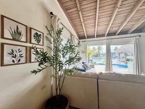 Ein Zimmer mit Holzboden, einer Couch, einer Topfpflanze und gerahmten Pflanzenbildern an der Wand.
