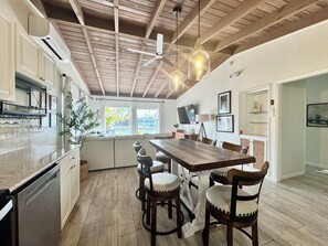 Eine moderne Küche mit Essbereich, Holzbalkendecke und Blick ins Freie.