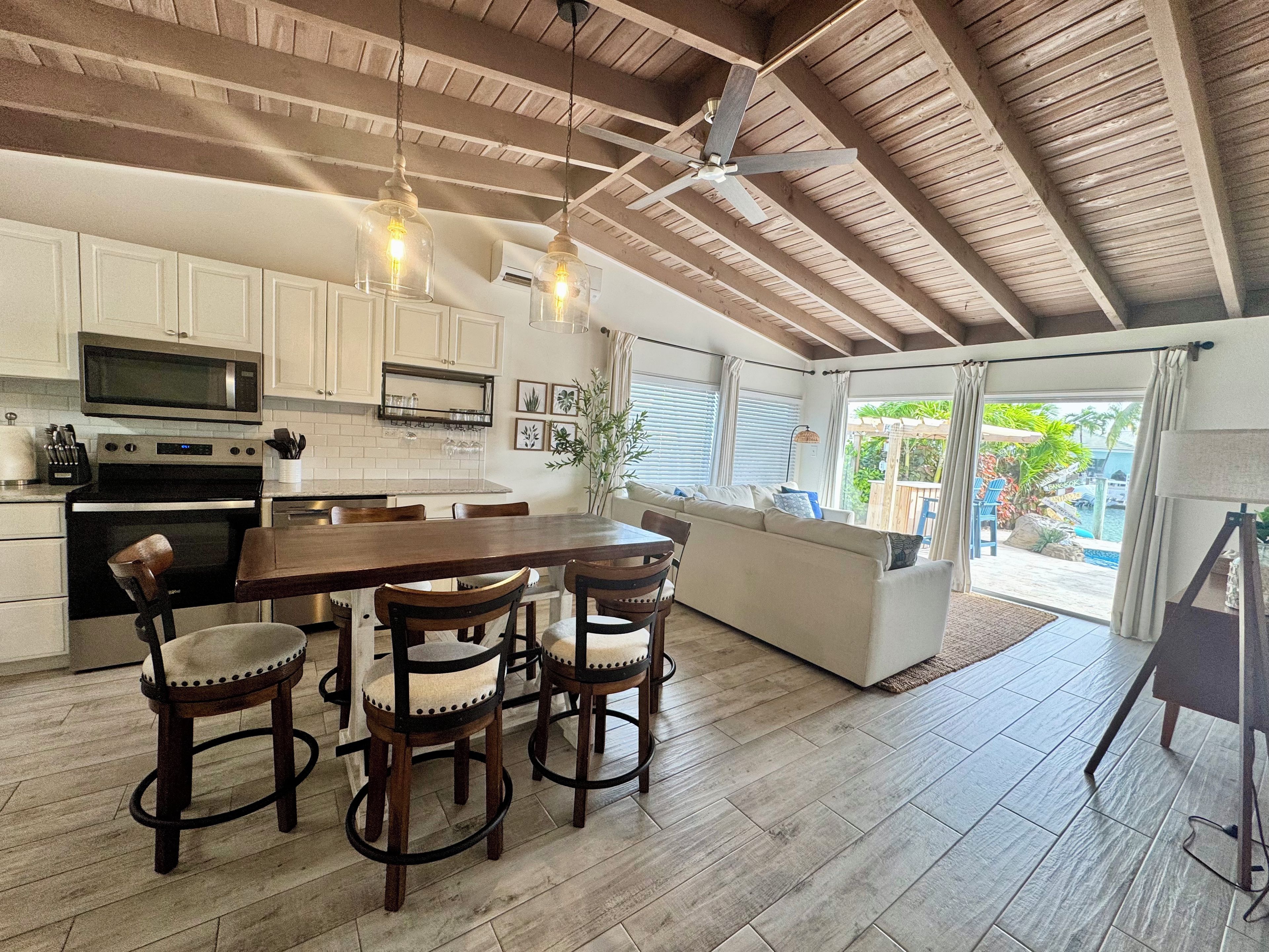 A spacious kitchen with white cabinets, a central island, and a dining area with wooden chairs.