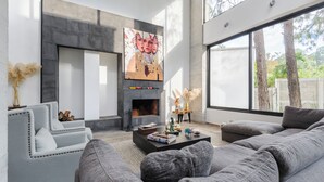 A modern living room with a fireplace, grey sofas, and a large painting on the wall. - Casa María (Valle de Bravo)